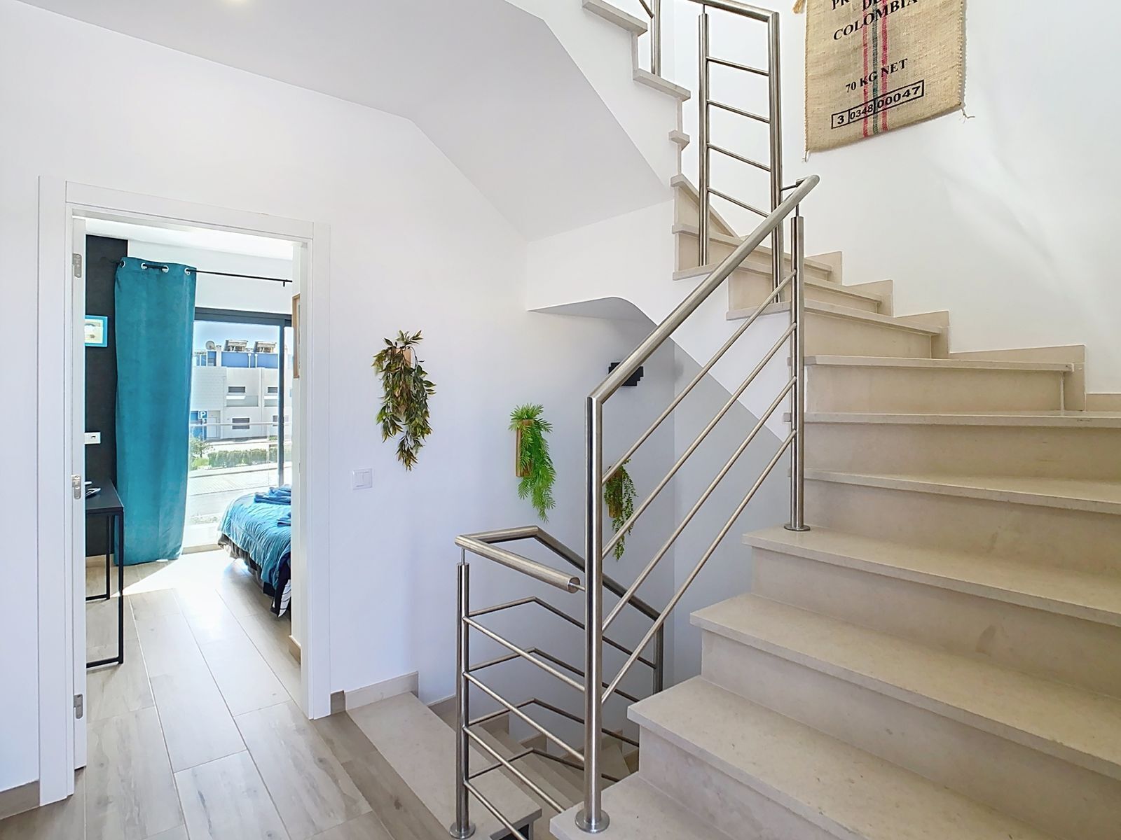 Una escalera con barandilla metálica que conduce a una plataforma. Hay dos plantas en macetas sobre la pared de la plataforma.