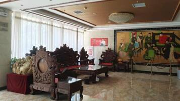 A lobby with ornate furniture, a large mural, and a chandelier.