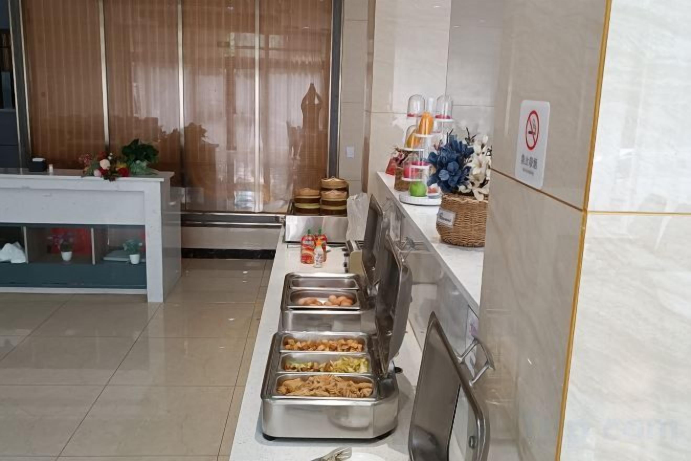 Zona de bufé con varios dispensadores de comida, un mostrador de recepción y un cartel de prohibición de fumar.