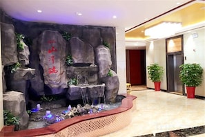 A reception area with a rock wall, a water feature, and potted plants.
