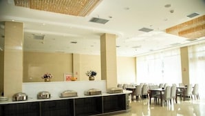 Een moderne hotel lobby met een receptiebalie, een zithoek en grote ramen.