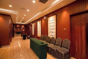 Un salón de conferencias con una larga mesa y sillas, paneles de madera en las paredes y un cartel con texto.