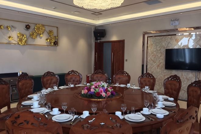 Un salón de conferencias con una mesa redonda, sillas y un centro de mesa floral.