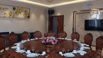 Un salón de conferencias con una mesa redonda, sillas y un centro de mesa floral.