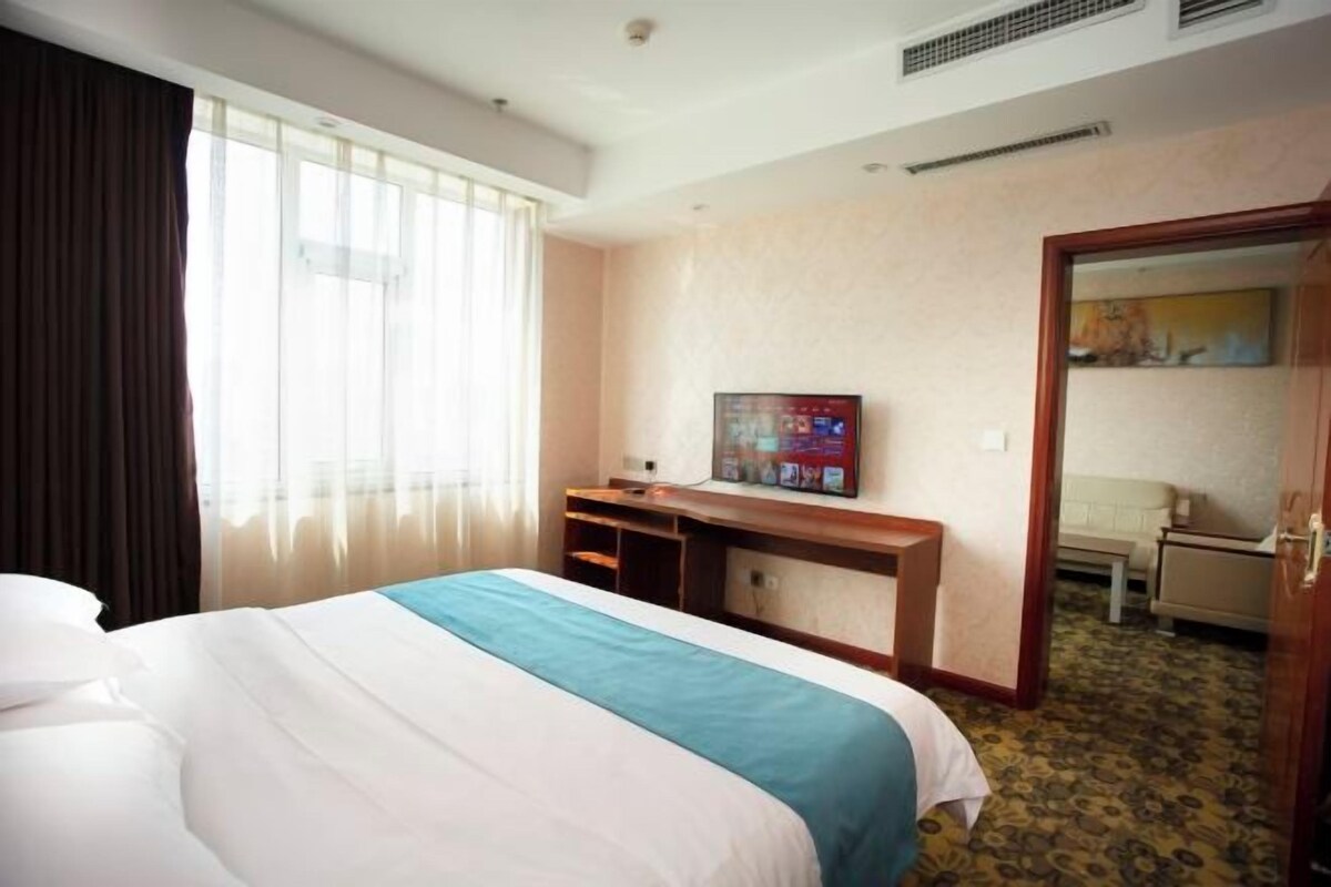 Een hotelkamer met een bed, een bureau, een televisie en een deur naar een badkamer.