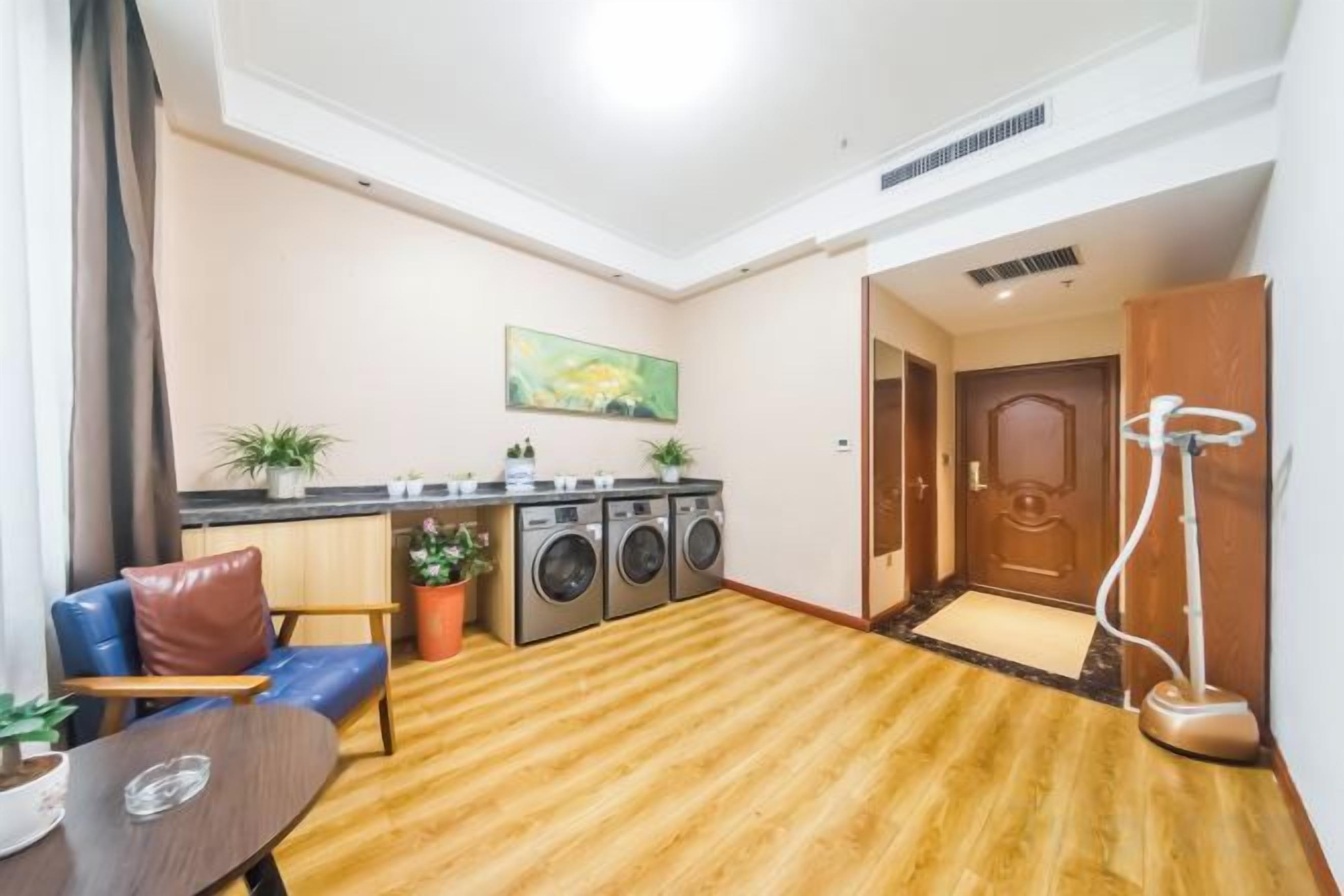 Un espacio habitable pequeño con sofá, una mesa, lavadora y aspiradora.