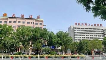A building with multiple floors and a flat roof, surrounded by trees and a yellow barricade.