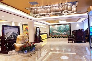 A spacious lobby with a high ceiling, a large painting, and a reception desk.
