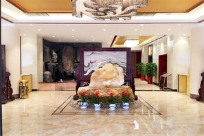 Eine Lobby mit einem großen Felsen als Mittelpunkt, einem Gemälde und einer Kristallleuchter.