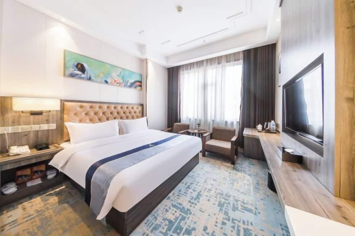 Habitación de hotel con una cama grande, un televisor, un escritorio y un cuadro en la pared.