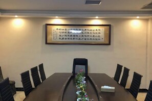 A conference room with a long table, chairs, and a framed quote on the wall.