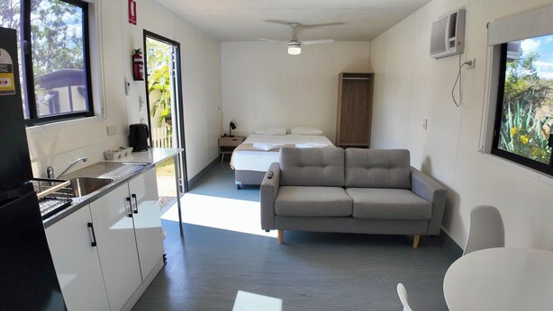 A compact hotel room with a kitchenette, a bed, a sofa, and a dining area. - MIDTOWN CARAVAN PARK (Millbank)