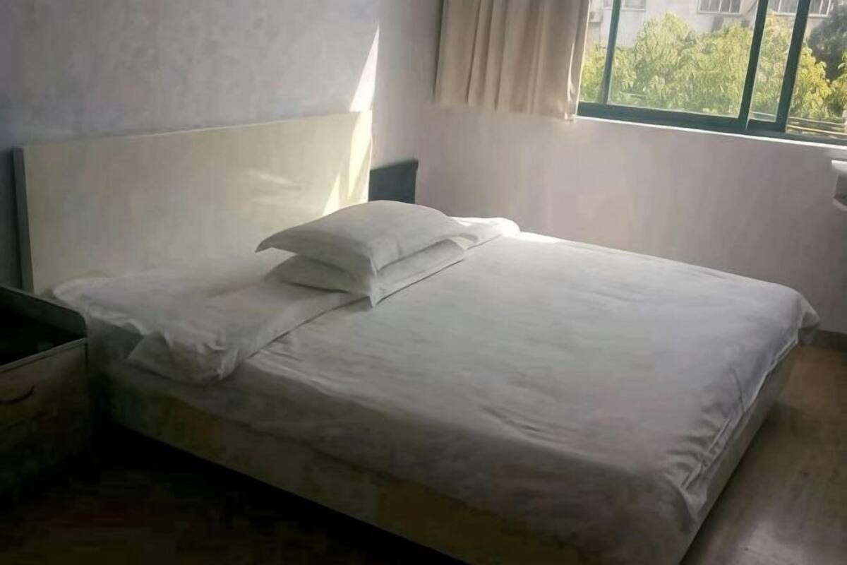 A bed with white bedding in a room with a window.
