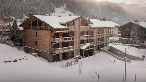Un refugio de madera de varios pisos con balcones, rodeado de montañas nevadas.