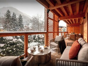 Un chalet en bois accueillant, doté d’un balcon offrant une vue sur un paysage montagneux enneigé.