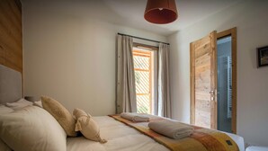 Un dormitorio con una cama grande, una puerta de madera y una ventana con cortinas.