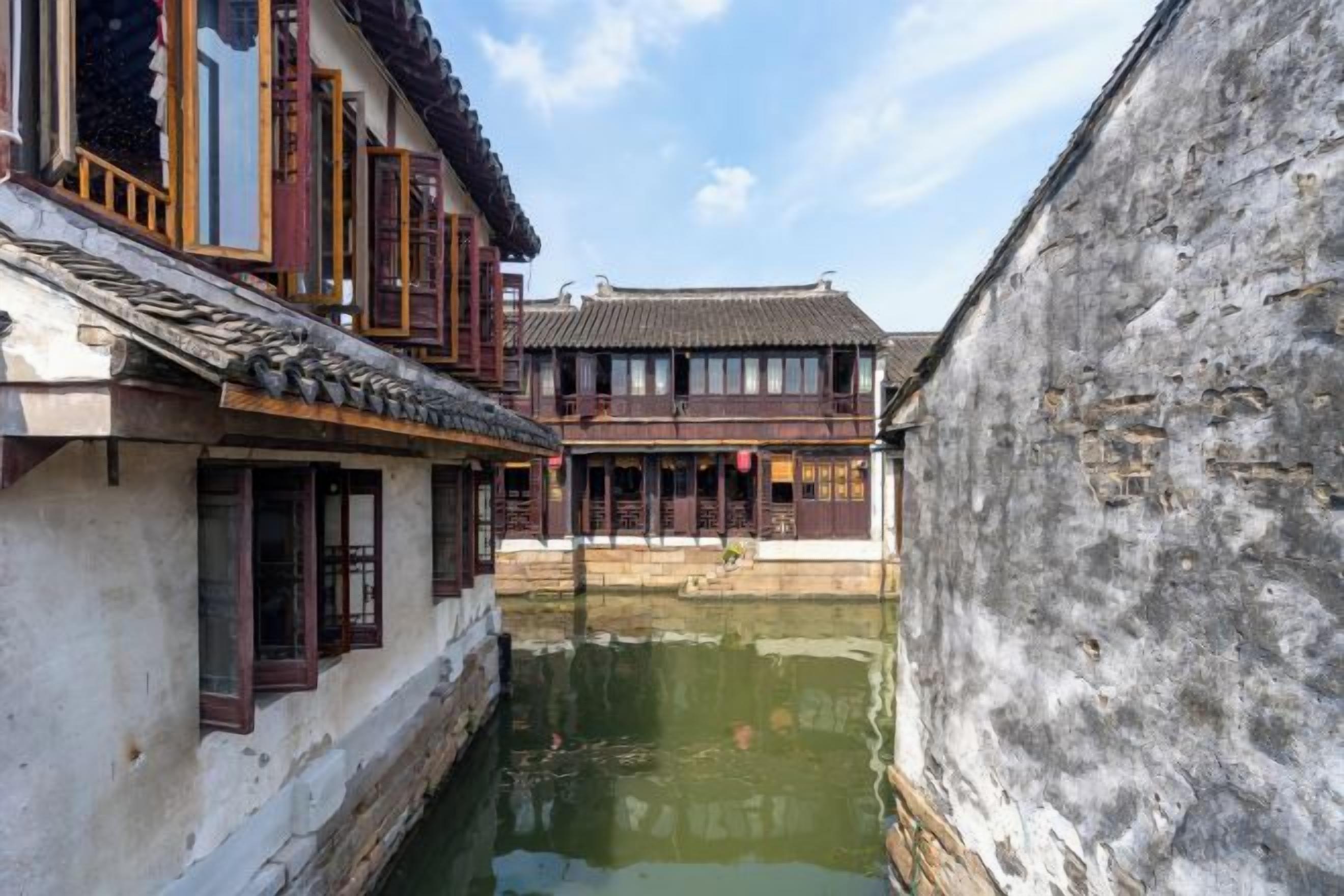 A narrow waterway between traditional buildings with wooden window frames and tiled roofs.