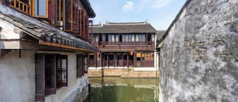 A narrow waterway between traditional buildings with wooden window frames and tiled roofs.