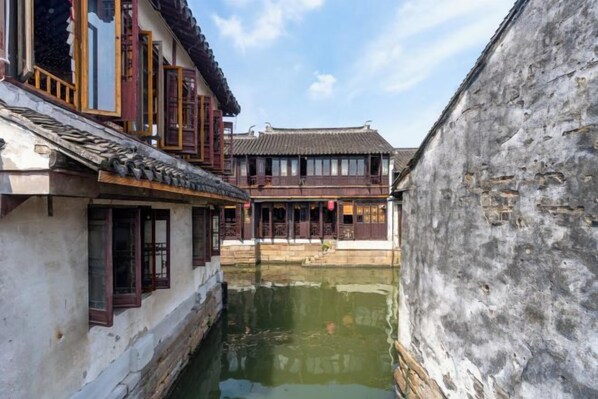 A narrow waterway between traditional buildings with wooden window frames and tiled roofs.
