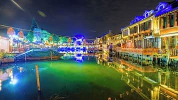 A nighttime view of a traditional-style building with a waterway in front, illuminated by colorful lights.