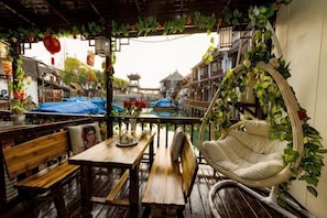 Un patio tradicional con muebles de madera, una silla colgante y plantas en macetas.