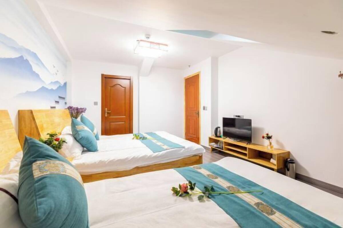 A hotel room with two beds, a television, and a wooden door.