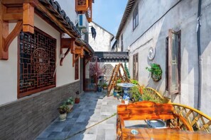 Une ruelle étroite aux bâtiments d’architecture traditionnelle, un banc en bois et des plantes en pot.