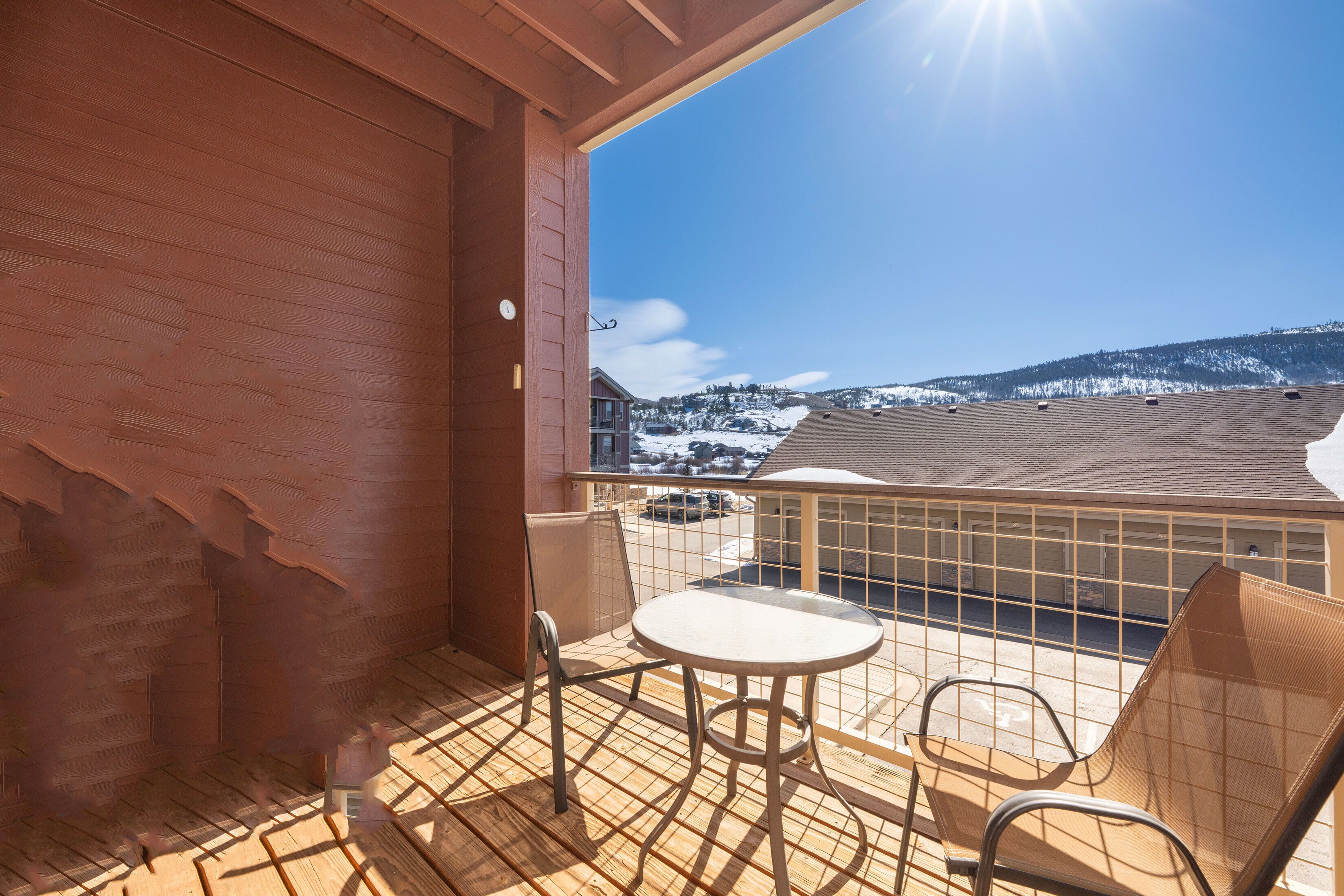 Un balcon donnant sur un paysage enneigé, avec une table et deux chaises.