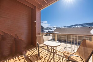 A balcony with a view of a snowy landscape, a table, and two chairs. - Ten Mile G-201 Wonderfully decorated and pet friendly two-bedroom (Granby)