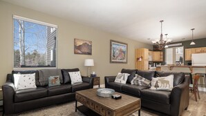 A living room with two dark leather sofas, a wooden coffee table, and a patterned rug. - Winterstar Building A #6 3 bedroom views, Pet friendly common area HT (Fraser)