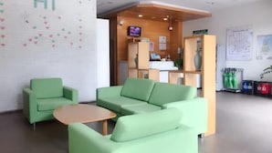 A reception area with a green sofa, a small table, and a TV screen. - Hi Inn (Shanghai Jinqiao Yanggao Middle Road) (Shanghai)