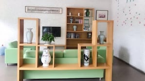 A modern living room with a green sofa, wooden shelves, and a flat-screen TV. - Hi Inn (Shanghai Jinqiao Yanggao Middle Road) (Shanghai)