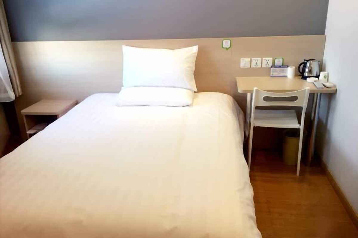 Une chambre d’hôtel avec un lit, un bureau, une chaise et une petite table.