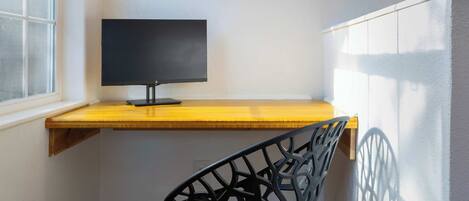 Un bureau d’angle avec un écran d’ordinateur, une chaise et une fenêtre.
