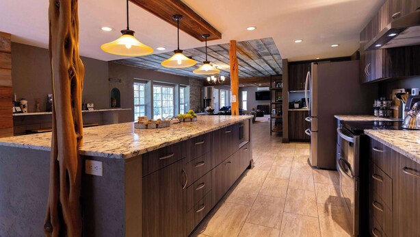 A modern kitchen with a large island, wooden cabinets, and pendant lighting. - Willie's Hill Country Hideaway - Stay for 8 With Hot Tub & Fire Pit (Wimberley)