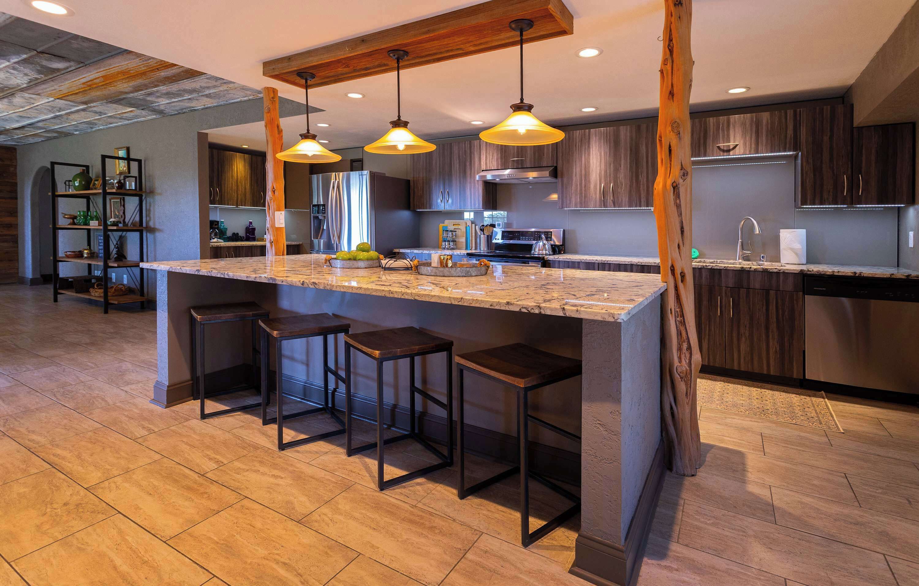 A modern kitchen with a large island, pendant lights, and bar stools.