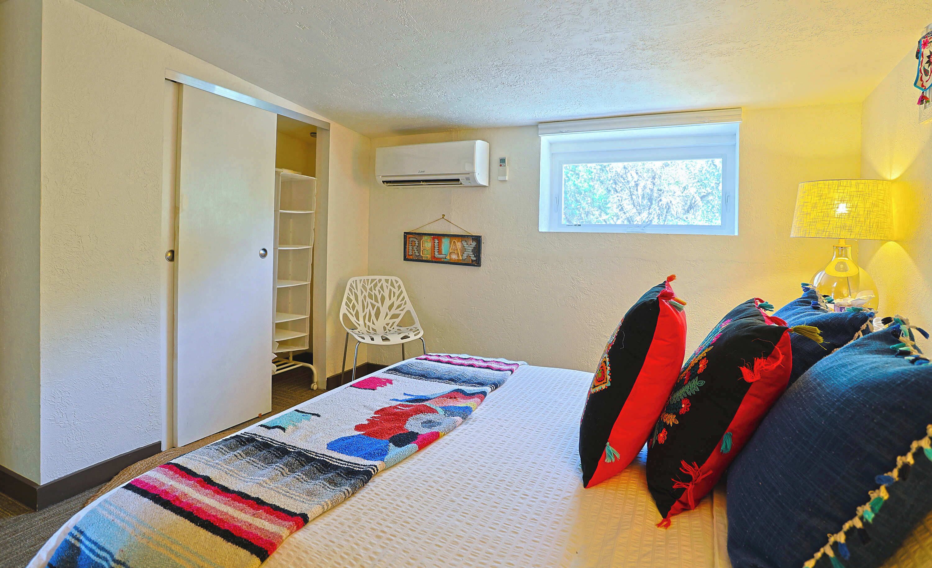 Une chambre à coucher avec un lit, une fenêtre, une chaise, une étagère et une lampe.