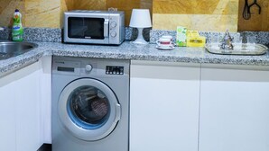 A compact kitchen with white cabinets, a microwave, a washing machine, and a sink. - Superb luxury apartment with terrace in Gueliz Marrakech (Marrakech)