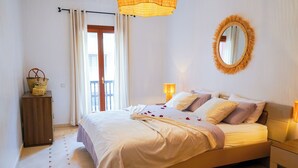 A bedroom with a bed, bedside tables, a mirror, a wooden wardrobe, and a balcony door. - Superb luxury apartment with terrace in Gueliz Marrakech (Marrakech)