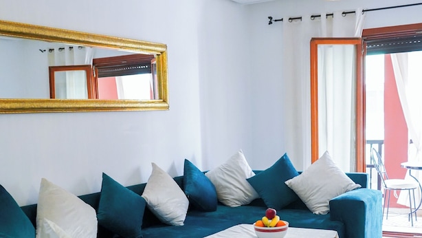 A modern living room with a teal sofa, a small table with a fruit bowl, and a hanging light fixture. - Superb luxury apartment with terrace in Gueliz Marrakech (Marrakech)