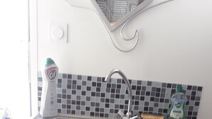 Una cocina con armarios oscuros, un lavamanos de acero inoxidable y un salpicadero de azulejos.