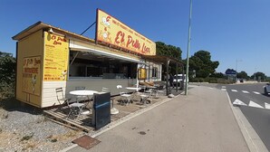 Un camión de comida llamado 'El Pollo Loco' con mesas al aire libre y un cartel de menú.
