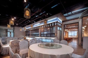 A modern hotel lobby with a round glass table, seating area, and a reception desk. - Mastery 101 Hotels (Nanning)