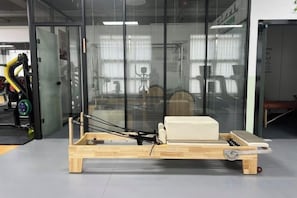 A wooden bed frame with a mattress and a pull-out drawer, situated in a room with large windows and a view of the outside. - Mastery 101 Hotels (Nanning)