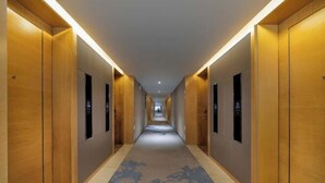 A hotel corridor with wooden doors, a patterned carpet, and recessed lighting. - Mastery 101 Hotels (Nanning)