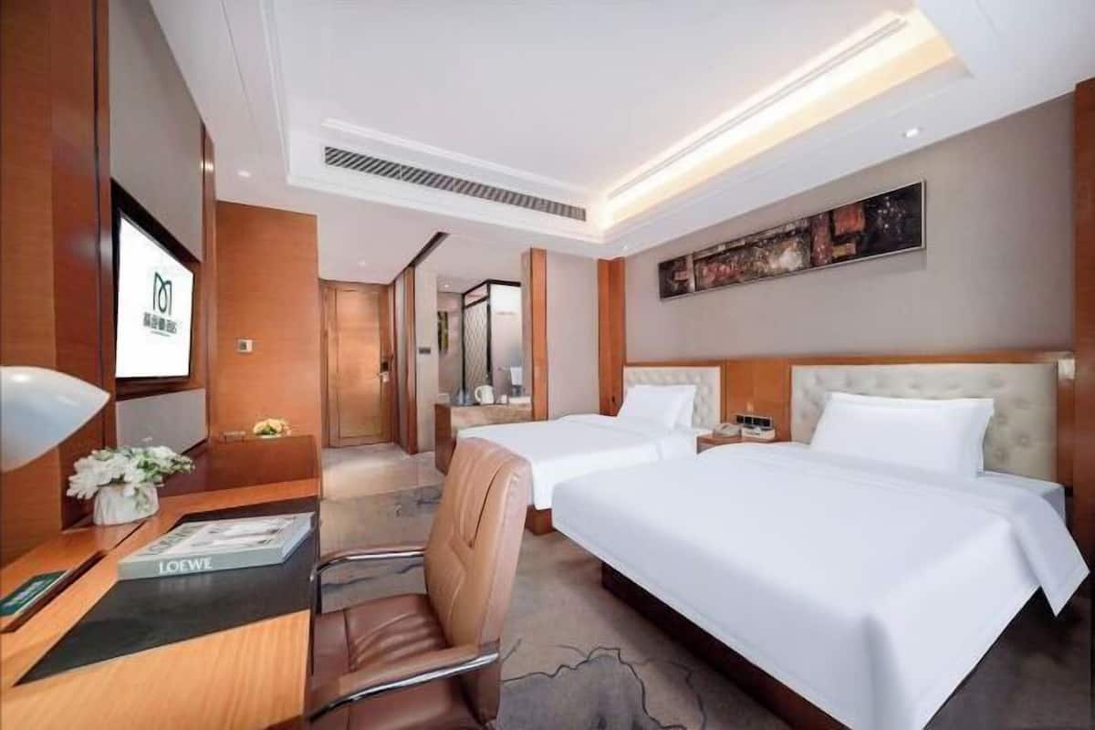 A hotel room with two beds, a desk with a chair, a TV, and a painting on the wall.