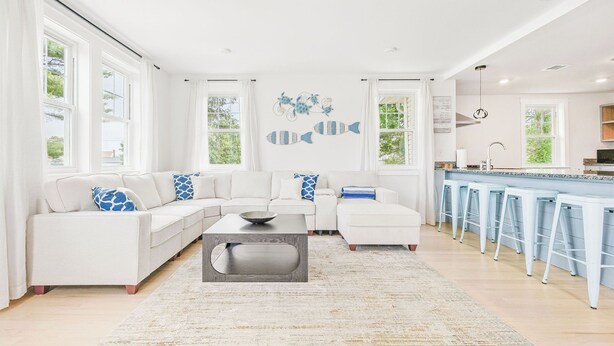 A modern living room with a white sofa, a coffee table, and a bar area with stools. - Spacious House on Sunset Lake 4 BR, 2 BA
Unit 2 on Top Floor (Braintree)