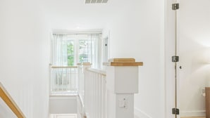 A staircase with wooden steps and white walls, leading to a landing with a window and a door. - Spacious House on Sunset Lake 4 BR, 2 BA
Unit 2 on Top Floor (Braintree)