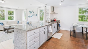 A modern kitchen with white cabinetry, a granite countertop, and a large island. - Spacious House on Sunset Lake 4 BR, 2 BA
Unit 2 on Top Floor (Braintree)