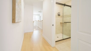 A hallway with wooden flooring, white walls, and a glass shower enclosure. - Spacious House on Sunset Lake 4 BR, 2 BA
Unit 2 on Top Floor (Braintree)